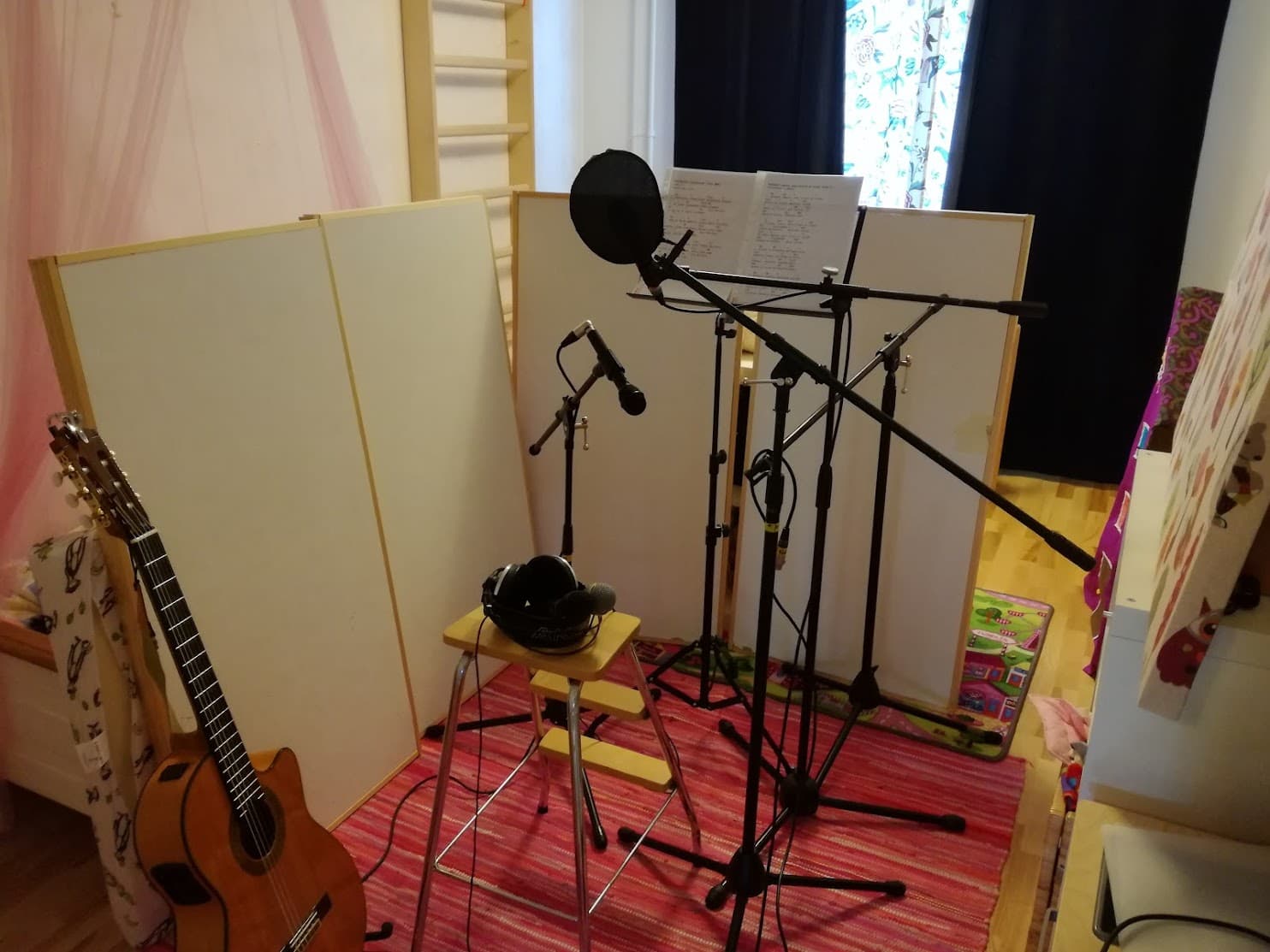 Kitaran äänittelyä huoneessa, sermejä ympärillä, mikrofoneja jalustoilla.