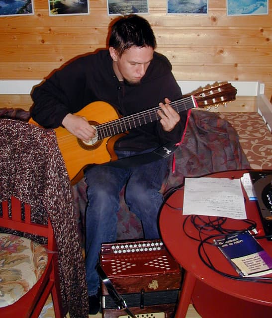 Minä soittamassa klassista kitaraa sohvalla.